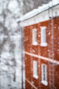 Snow falling in front of a red brick building
